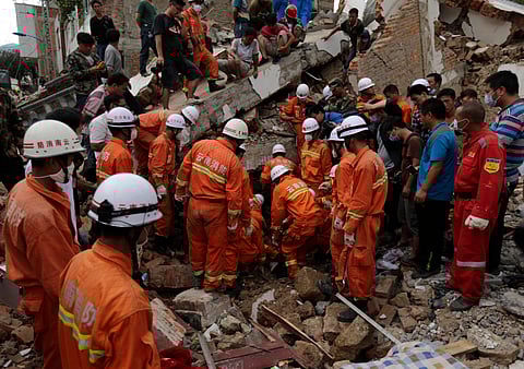 Rescuers try to retrieve a trapped victim's body from a collapsed house following a massive earthquake in the town of Longtoushan in Ludian County in southwest China's Yunnan Province, in August 2014