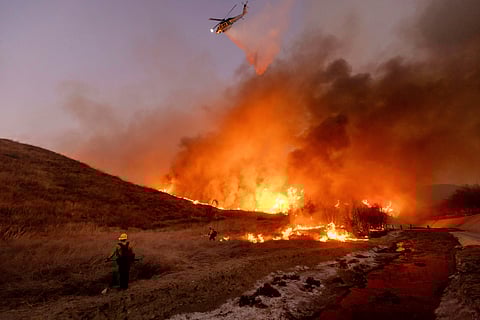 Firefighters watch as water is dropped on the Palisades Fire in Mandeville Canyon Saturday, Jan. 11, 2025, in Los Angeles.