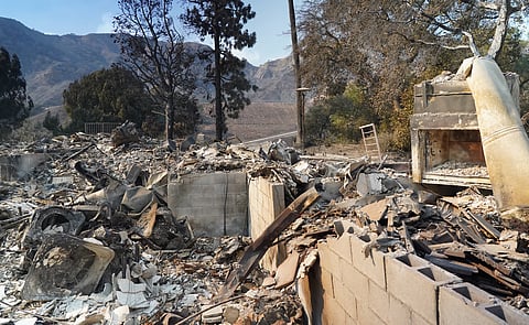 Firefighters watch as water is dropped on the Palisades Fire in Mandeville Canyon Saturday, Jan. 11, 2025, in Los Angeles.