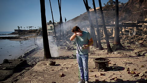 Man reacts as he sifts through the remains of his father's fire-ravaged beach front property in the aftermath of the Palisades Fire Friday.