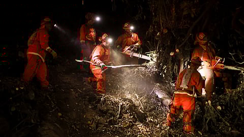 A California Department of Corrections hand crew works containment lines ahead of the Palisades Fire Tuesday, Jan. 14, 2025.