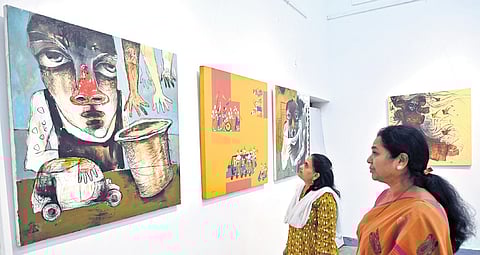 Art lovers keenly observe paintings on display at an exhibition at Karnataka Chitrakala Parishath in Bengaluru on Sunday |