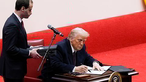 President Donald Trump signs an executive order at an indoor Presidential Inauguration parade event in Washington.