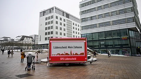 A woman with a walking aid moves past an election campaign trailer of the Social Democratic Party SPD in the pedestrian zone of Luedenscheid, western Germany, on January 16, 2025. 