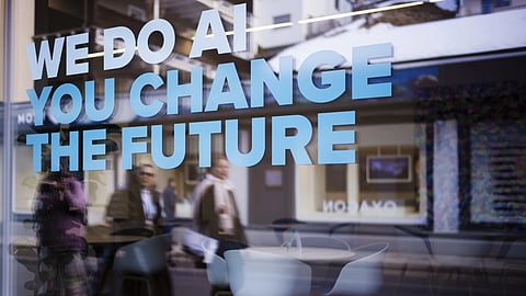 People reflected in a window with a slogan about AI at a representation of a company ahead of the World Economy Forum in Davos, Switzerland, Sunday, Jan 19, 2025