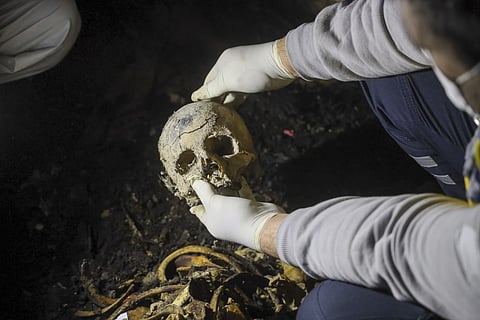 A Syrian civil defense worker, known as a White Helmet holds a skull while inspecting human remains found in two separate basements in Sbeneh, outskirts of Damascus, Syria, Tuesday, Jan 28, 2025.