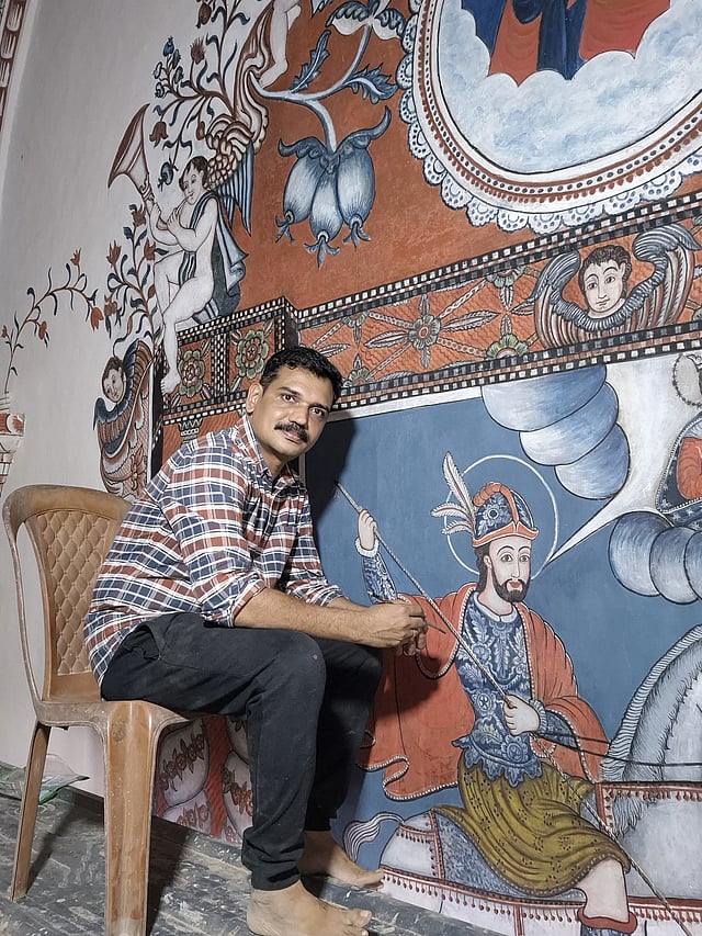 Artist V M Jijulal painting the mural of St George