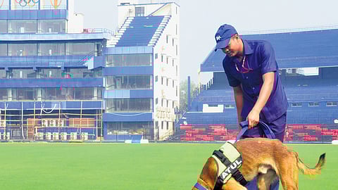 A security personnel along with a sniffer dog carries out a safety check around the pitch, ahead of the India-England ODI at Barabati Stadium in Cuttack 
