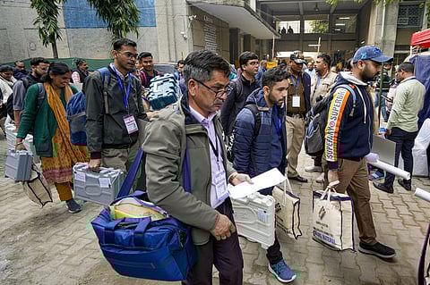 Polling officials leave after collecting election material from a distribution center on the eve of the Delhi Assembly elections.