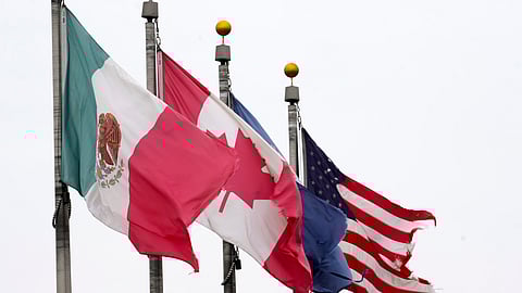 The flags of Mexico, Canada and the United States are shown near the Ambassador Bridge, Monday.
