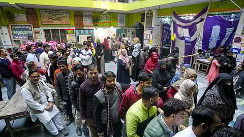 People wait in queues to cast their votes during the Delhi Assembly elections, at Jafrabad, in New Delhi.