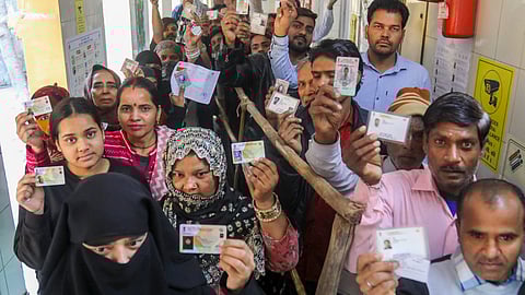 Voters show their ID cards as they wait in queues at a polling booth.