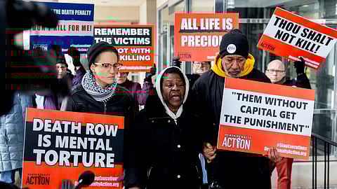 Lizz Schallert, left, and Charles Keith, right, stand in solidarity with Carol Frazier, mother of Demetrius Frazier, as she pleads publicly Tuesday, Jan. 28, 2025, in Lansing, Mich., to Gov. Gretchen Whitmer to bring home her son Demetrius.