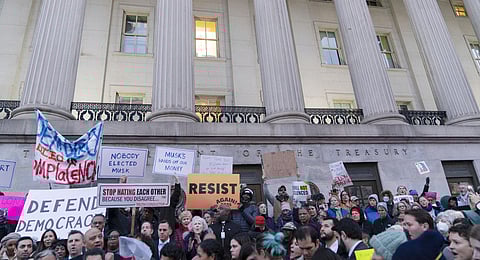 People listen to speakers during a rally against Elon Musk outside the Treasury Department in Washington, Tuesday, Feb. 4, 2025. 
