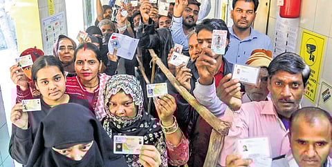 Voters show their ID cards as they wait in queues at a polling booth to cast votes during the Delhi Assembly elections, at Shahzada Bagh in New Delhi, Wednesday, Feb. 5, 2025.