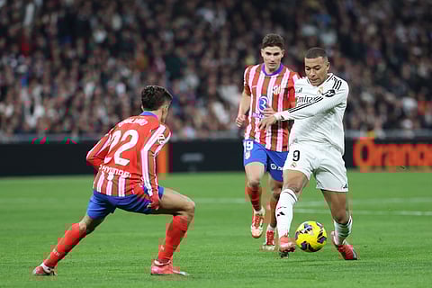 Real Madrid's Kylian Mbappe (R) is challenged by Atletico Madrid's forward Julian Alvarez (C) and Giuliano Simeone during the Spanish league football match between Real Madrid CF and Club Atletico de Madrid on February 8, 2025. 