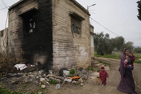 Palestinian Yasmin al-Tirawi and her children walk around their house, which was recently set on fire by Israeli settlers, near the Murab'a Israeli army checkpoint, in the West Bank village of Burin, near Nablus, Monday, Feb 3, 2025.