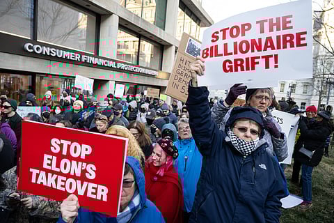 Demonstrators hold signs as they protest against US President Donald Trump and DOGE Elon Musk's anticipated plan to close the Consumer Financial Protection Bureau in front of the CFPB headquarters in Washington, DC, February 10, 2025. 