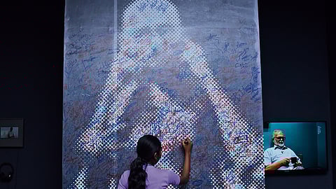 A visitor adds her signature to the Gandhi installation at the exhibition