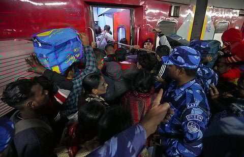 New Delhi: Security personnel assist passengers boarding a train at the New Delhi Railway Station, in New Delhi, Sunday, Feb. 16, 2025.