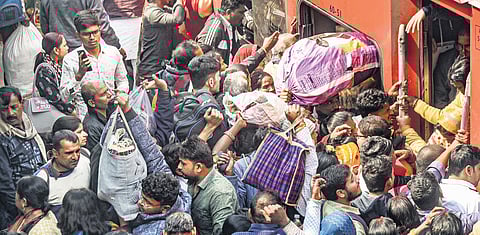 Passengers try to board an overcrowded train amid a huge rush owing to Mahakumbh Mela, at Patna railway station on Monday.