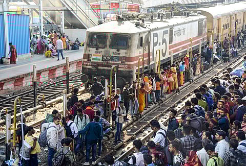Passengers wait on the tracks to board a train to the Mahakumbh (Photo | PTI)