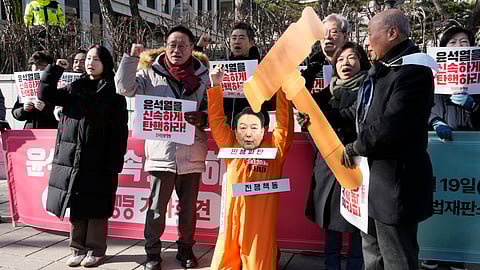 A protester wearing a mask of impeached South Korean President Yoon Suk Yeol attends with his fellow protesters during a rally calling for Yoon to step down in front of the Constitutional Court in Seoul, South Korea, Wednesday, Feb. 19, 2025. The signs read "Impeach Yoon Suk Yeol quickly."