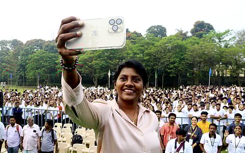 Anitha Pauldurai is taking a selfie with the spectators in the background.