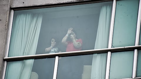 Migrants deported from the United States wave to the press from inside a hotel in Panama City, Wednesday, Feb. 19, 2025. 
