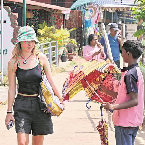 A boy trying to sell an umbrella to a foreign tourist at Papanasam beach in Thiruvananthapuram
