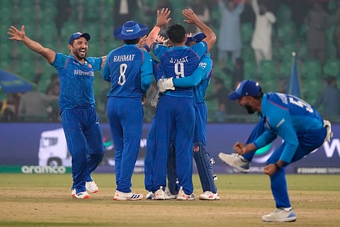 Afghanistan's Azmatullah Omarzai, center, and teammates celebrate after winning the ICC Champions Trophy cricket match against England, in Lahore, Pakistan.