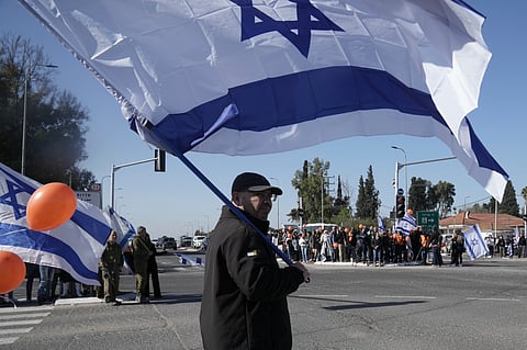Israelis gather on the side of a road where the funeral convoy carrying the coffins of slain hostages Shiri Bibas and her two children, Ariel and Kfir, will pass by near Kibbutz Yad Mordechai.