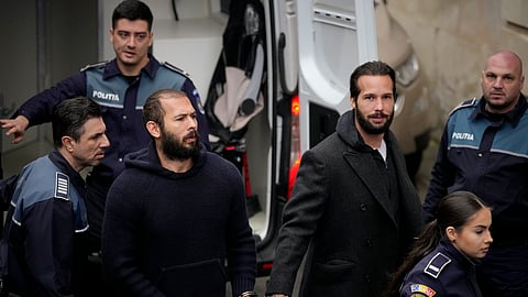 Police officers escort Andrew Tate, center, handcuffed to his brother Tristan Tate, to the Court of Appeal in Bucharest, Romania, Monday, Feb. 27, 2023.