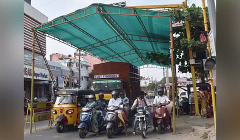 Coimbatore Corporation installs green shade nets at Selvapuram traffic junction to provide relief from sweltering heat for motorists in Coimbatore on Wednesday. 