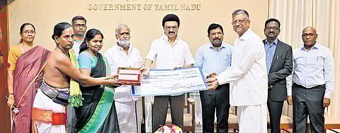 The chief minister handing over cheques worth Rs 27 crore to TN temples