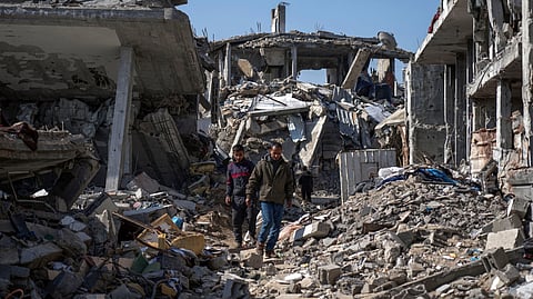In this photo from Feb. 17, 2025, Palestinians walk amid the rubble of homes, destroyed by the Israeli army's air and ground offensive against Hamas in in Bureij refugee camp, central Gaza Strip. 