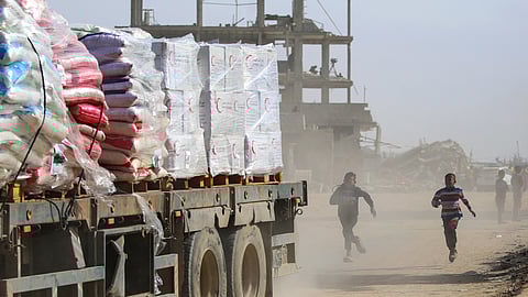 Palestinian children chase after a truck loaded with humanitarian aid as it drives through Rafah in the southern Gaza Strip after crossing through the Kerem Shalom crossing.
