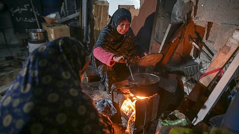 Fatima Al-Absi prepares food for her family's iftar, the fast-breaking meal, on the first day of Ramadan in their damaged apartment in Jabaliya, northern Gaza Strip, on Saturday, March 1, 2025. 