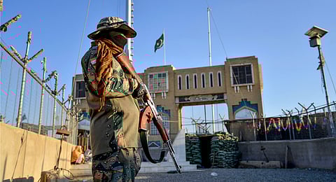 An Afghan security personnel stands guard at a fenced corridor of the Afghanistan-Pakistan border in Spin Boldak district, Kandahar province.