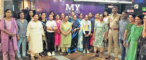 A group of women poses for a photograph with police personnel after watching a film at a cinema as part of the Urappu initiative of the Ernakulam Rural police 