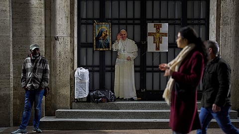 People walk past a cardboard cutout with the image of Pope Francis near St. Peter's Square in Rome, Saturday.