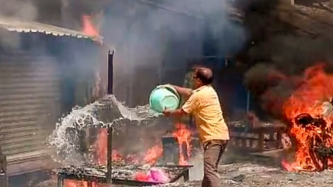 A man tries to douse a fire which broke out at a firecracker shop, in Jharkhand's Garhwa on Monday. 