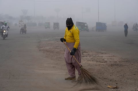 A sweeper cleans as smog envelops the area and reduces visibility in Lahore, Pakistan, Jan. 11, 2024.