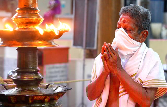 A man prays with his face covered at a temple in Kozhikode 