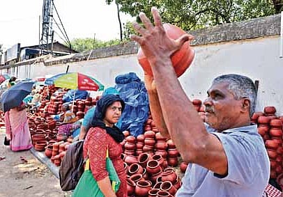 A devotee checks on an earthen pot kept for sale at East Fort