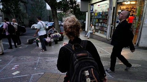 An Iranian woman, without a mandatory headscarf, or hijab, walks in downtown Tehran, Iran, June 10, 2024.