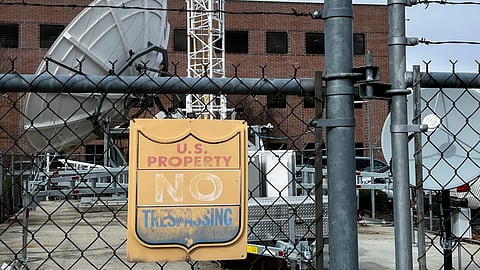 A chain link fence protects a satellite station and other equipment behind the Bureau of Reclamation office.