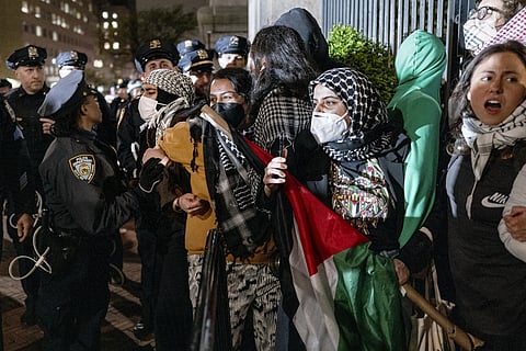 Demonstrators hold their ground near a main gate at Columbia University in New York, Tuesday, April 30, 2024, as New York City police officers move to clear the area after a building was taken over by pro-Palestinian protesters earlier in the day.