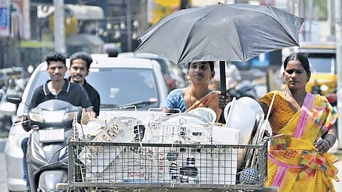 Women vendors shield themselves from heat with umbrellas in Karimnagar.