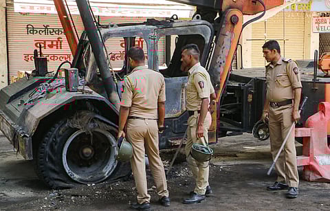 Police personnel near charred remains of a vehicle, a day after violence broke out following an agitation by a right-wing group demanding removal of Aurangzeb's tomb, in Nagpur.
